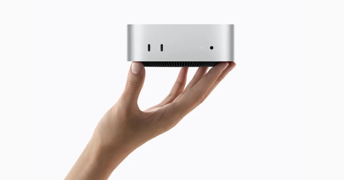 Un Mac mini tenu dans une main ouverte, sur fond clair